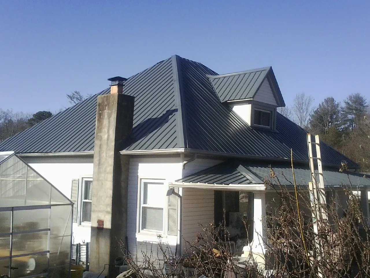 Dark blue standing seam metal roof on a white farmhouse with dormer — Slate & Tile Roof Repair by Roofing Brothers in Lacey