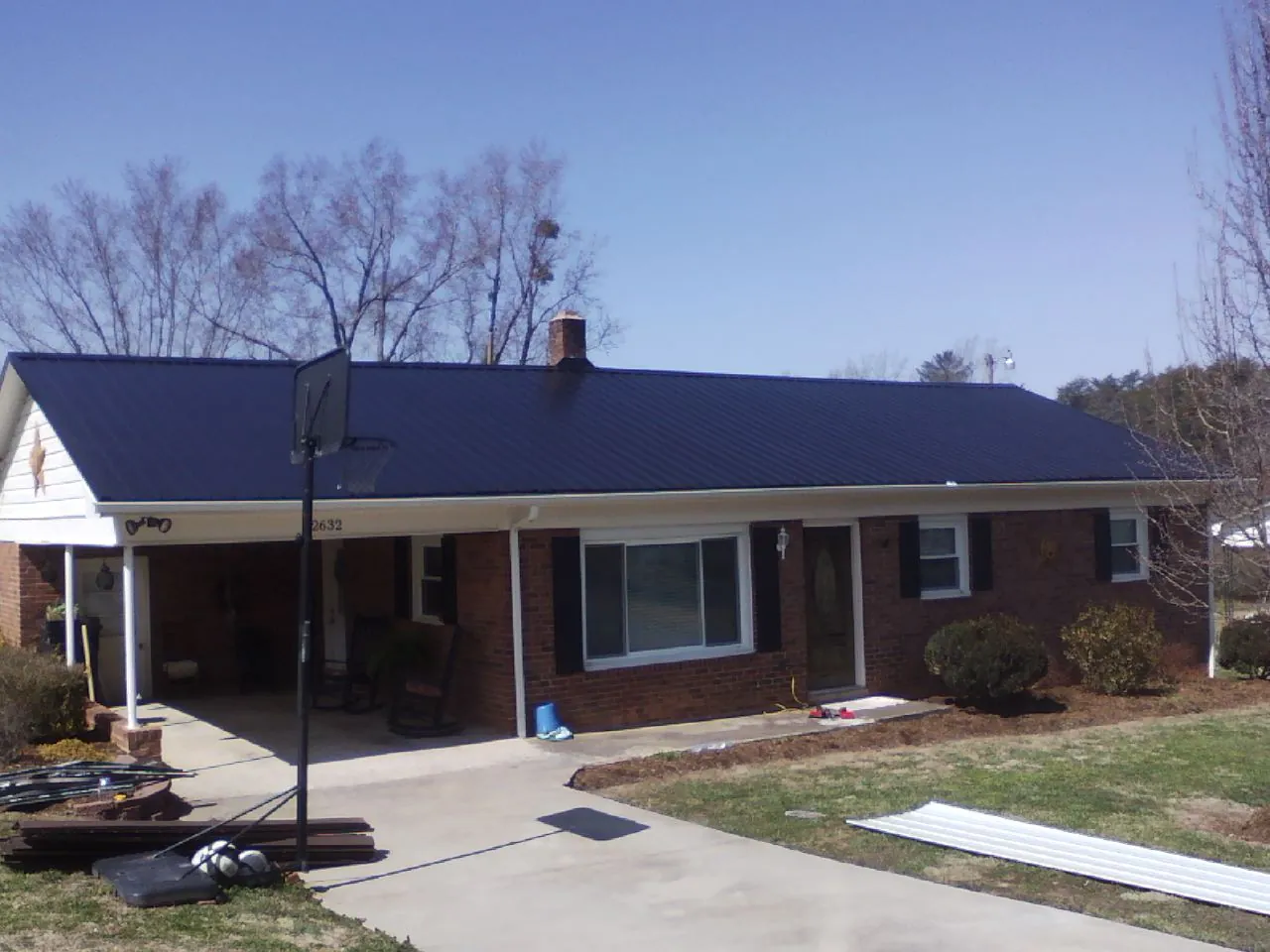 Finished dark blue metal roof on a brick ranch with a carport in Lacey