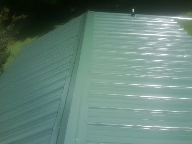 New green metal panels meeting at the ridge of a roof — Flat Roof Repair work by our crew in Lacey