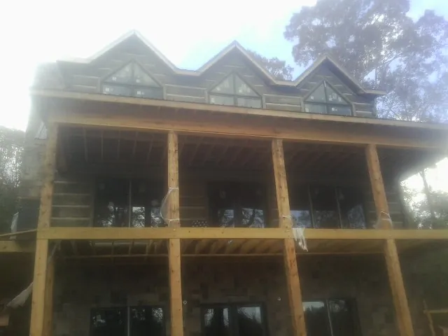 Dormers and porch framing on a large log home under construction — Roof Coating work by our crew in Lacey