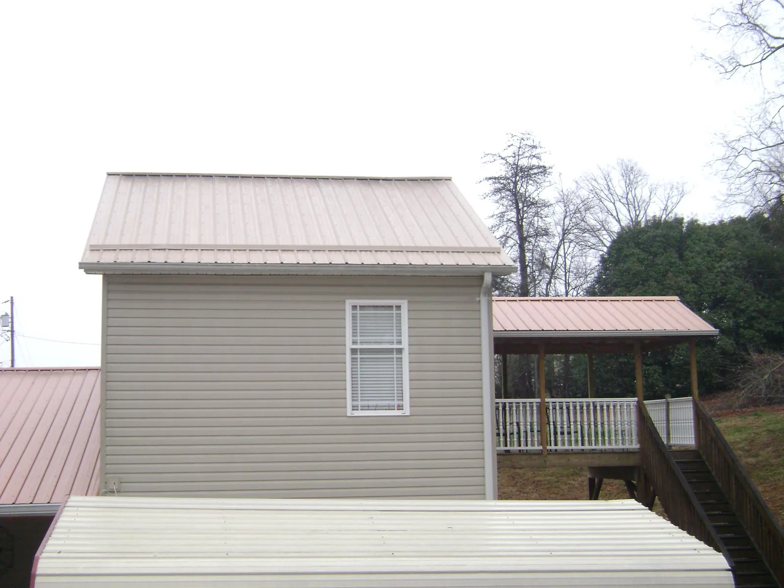 Tan metal roofs on a two story addition and attached porch, from a Roof Replacement job in Lacey